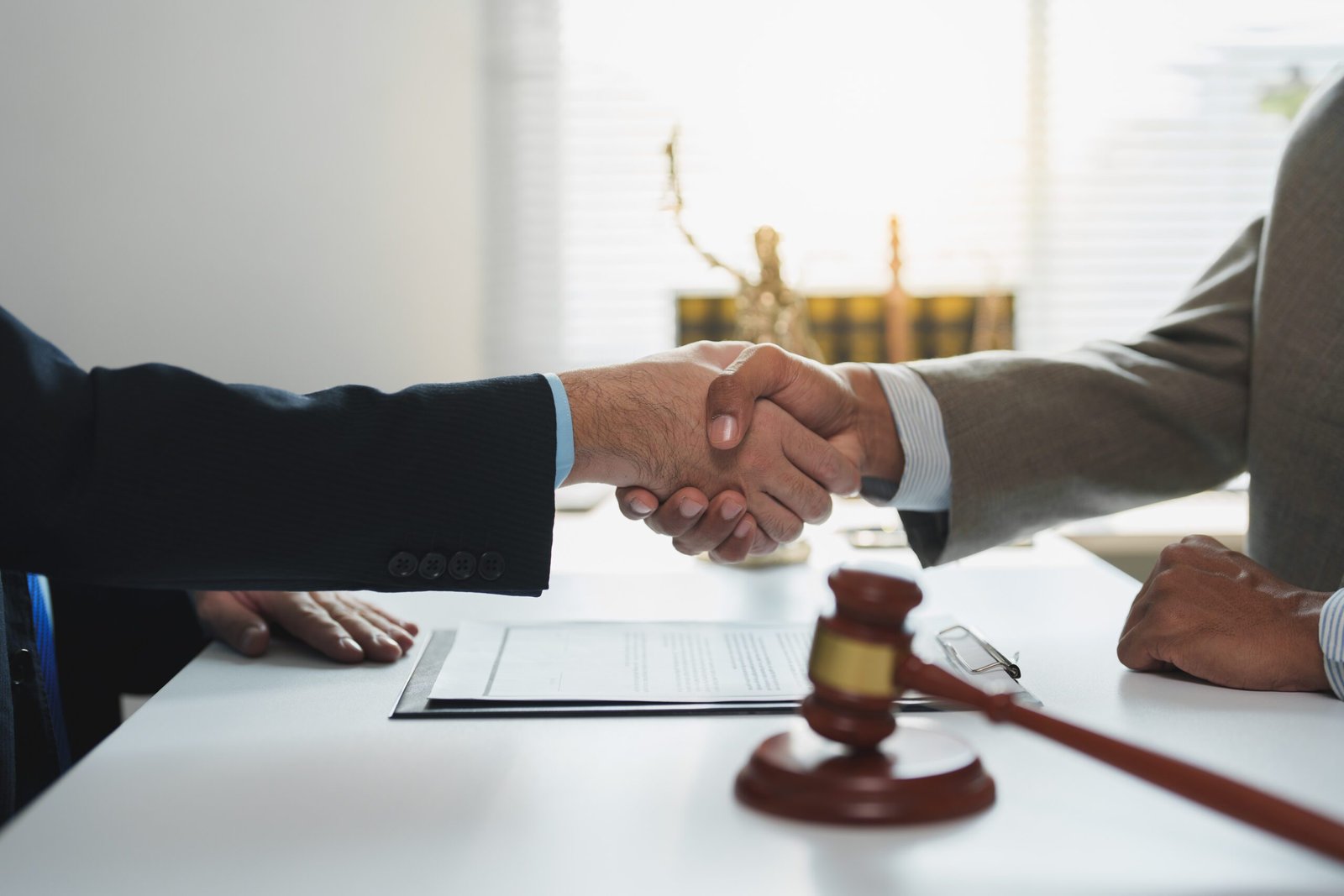 two lawyers are shaking hands after successfully negotiating and signing a legal contract, symbolizing agreement and cooperation in a law office setting with a gavel on the table